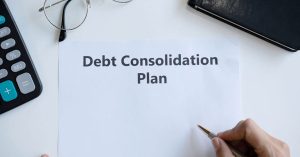 Man about to write on a sheet with 'Debt Consolidation Plan' printed on it