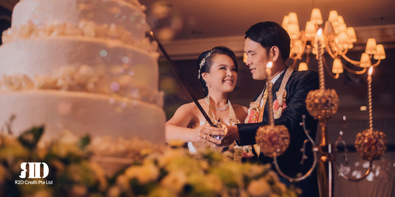 Couple at their wedding smiling at each other in the background while in the foreground there is a wedding cake