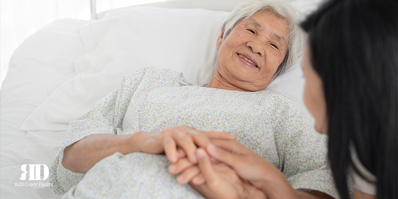 Smiling old lady in the hospital holding the hand of a younger lady