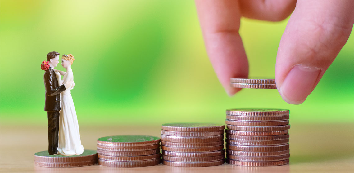 A mini figurine of a wedded couple beside a row of stacked coins in ascending order, representing the costs of a wedding