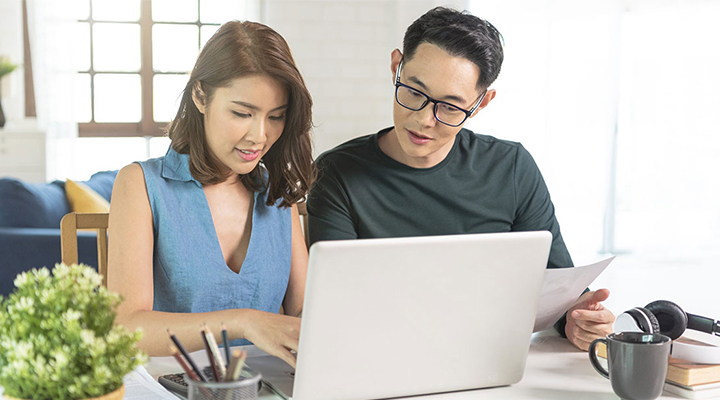 Young couple looking for the best personal loan on their laptop together at home