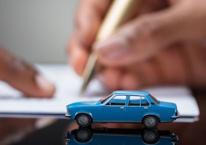 Blue model car on a desk as a man shows another man where to sign on a contract