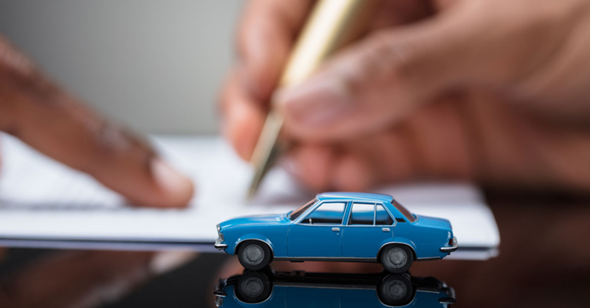 Blue model car on a desk as a man shows another man where to sign on a contract