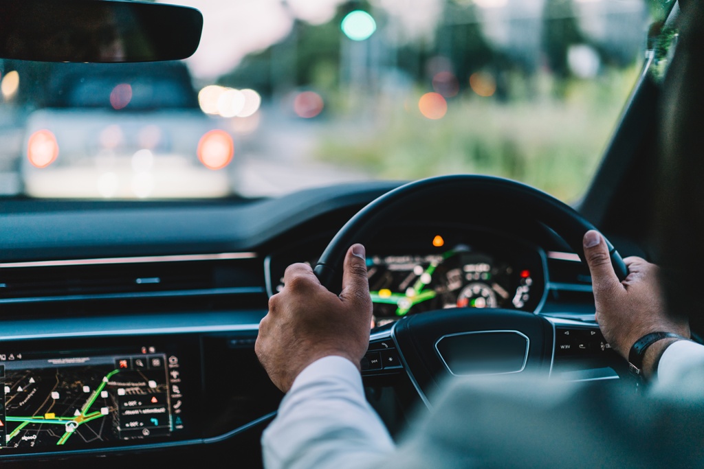 Back cropped view car wheel and male driver on a road driving without worries as he has a Grab personal loan