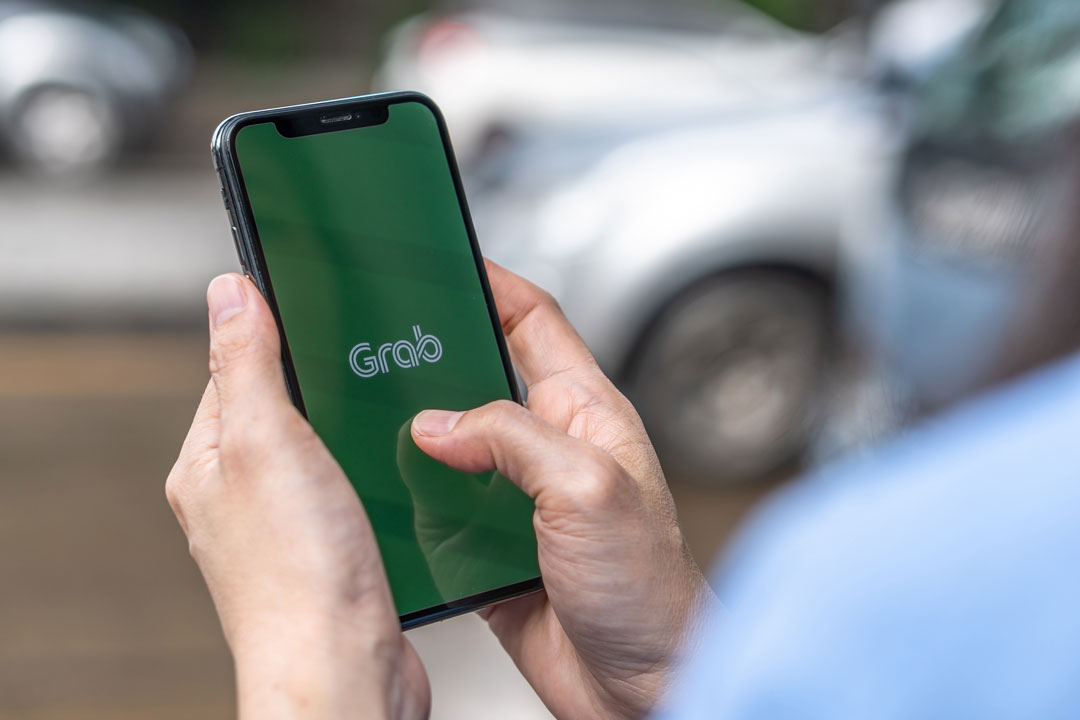 The Grab logo takes center stage as the app loads on a mobile phone, showing the wide reach of Grab Finance.