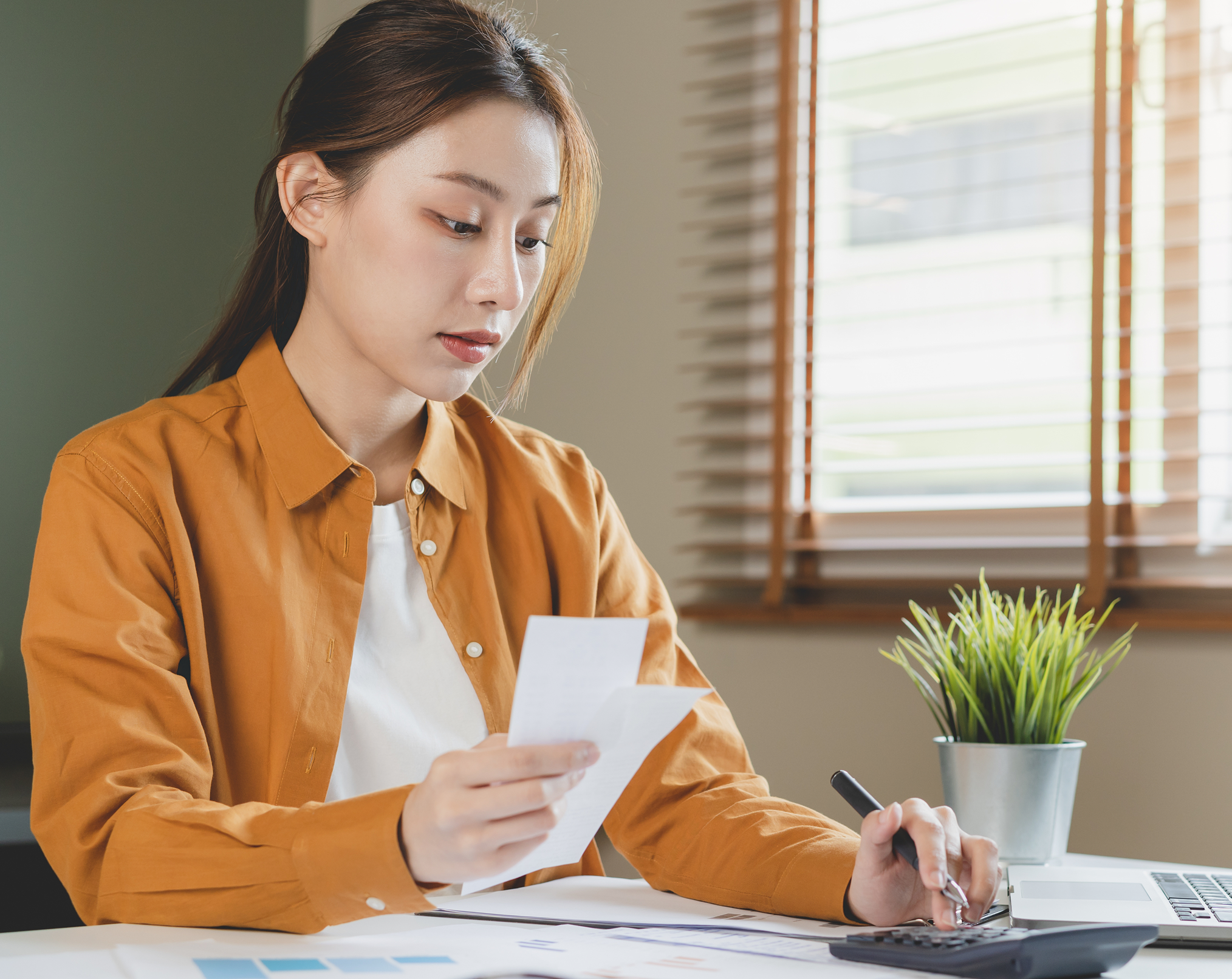 A lady using a calculator while checking this month's bill statements to see how huge of a payday loan sum she needs